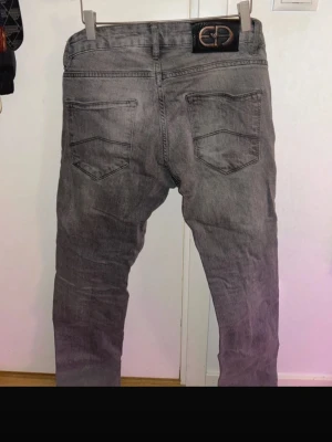 Armani jeans - Säljer ett par grå jeans med tvättad look och raka ben. Jeansen har fem fickor, bälteshällor och knappgylf. Snygg detalj med kontrastsömmar och klassisk passform. Perfekta till en avslappnad streetstil. 30/34