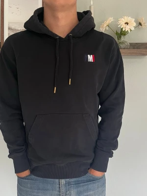 Svart hoodie från AMI Paris - Snygg svart hoodie från AMI Paris med broderad logga i vitt, blått och rött på bröstet.