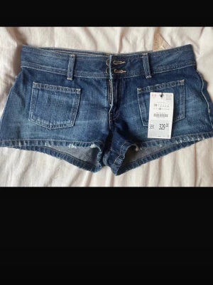 Mörkblå denimshorts med dubbla knappar - Snygga mörkblå denimshorts med dubbla knappar i midjan och klassiska fickor fram och bak. Shortsen har bälteshällor och råa kanter nedtill för en avslappnad look. Säljer även på Vinted: Nicoleiis
