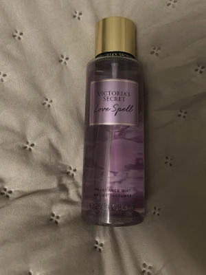 Victoria's Secret Love Spell mist - Fräsch och feminin body mist från Victoria's Secret i doften Love Spell. Flaskan är genomskinlig med lila också i bakruddn och har ett elegant guldigt lock. Rymmer 250 ml och har en stilren design som passar perfekt som en vardaglig men även på speciella tillfällen 