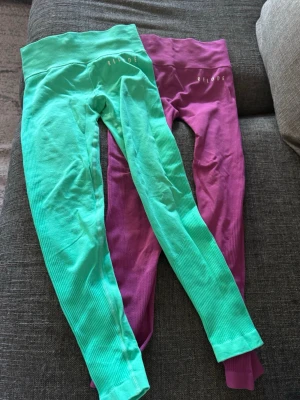 Två par ribbade leggings från Relode - Säljer två par ribbade leggings från Relode, ett par i mintgrönt och ett par i lila. Båda har hög midja och stretchigt material som sitter skönt på kroppen. Perfekta för träning eller chill. Snyggt ribbade detaljer längs hela benen.