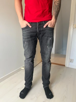 Svarta repeat Anbass - Säljer ett par svarta slim fit jeans med diskreta slitningar och tvättade detaljer. Jeansen har klassisk femficksmodell och normal midja. Snyggt slitna för en avslappnad look och passar perfekt till en streetwear-stil. Ny pris 1700kr