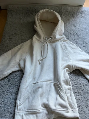Vit hoodie från Bik Bok med huva - Säljer en enkel och stilren vit hoodie från Bik Bok i storlek XS. Hoodien har en stor huva med dragsko, magficka och mjukt material på insidan. Perfekt för chill dagar eller när du vill ha en clean look.