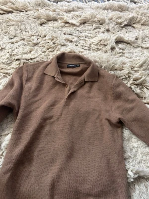 Beige stickad pikétröja J.Lindeberg - Säljer en beige stickad pikétröja från J.Lindeberg. Tröjan har klassisk krage, knäppning med två knappar och lång ärm. Materialet är mjukt och har en diskret struktur.