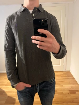 Grå Ralph Lauren långärmad piké  - Säljer denna sjukt snygga rugbytröjan från Ralph Lauren⭐️ Färgen är grå och storleken är M✅ Den har inga defekter och skicket är utomordentligt🙌🤝 Sjukt najs passform och passar perfekt till hösten☀️🙌 Tveka inte på att höra av er dig vid minsta fråga eller fundering😊