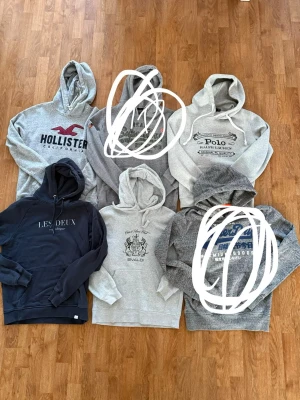 6-pack hoodies i olika märken och färger - Alla är storlek S Säljer ett paket med sex hoodies från Hollister, Superdry, Polo Ralph Lauren, Les Deux och Ewald. Färgerna är grå, mörkblå och melerad. Alla har huva och långa ärmar, vissa med tryck framtill och snörning i huvan. Perfekt för dig som vill ha variation i garderoben.