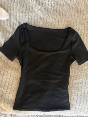 svart topp med urringning - snygg svart topp med korta ärmar och urringning, perfekt basplagg, jätteskönt material!! använd en gång och inga defekter