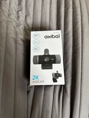(Ej använd) Exibel 2K QHD Webcam med autofokus - Säljer en svart Exibel 2K QHD-webbkamera med autofokus, brusreducerande mikrofon och vidvinkellins. Kameran har sekretesslucka och fäste för skärm upp till 3 cm. Ansluts via USB 2.0 och funkar till både PC och Mac.