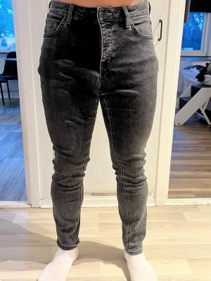 Svarta skinny jeans med hög midja - Säljer ett par svarta skinny jeans med hög midja och klassisk femficksdesign. Jeansen har en tvättad look och smal passform hela vägen ner. Perfekta till sneakers eller boots och passar dig som gillar en tajt siluett.