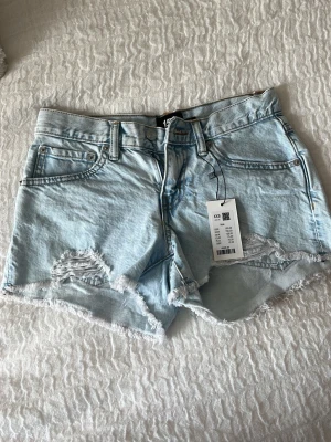 Ljusblå jeansshorts   - Snygga ljusblå denimshorts med fransig kant och slitna detaljer framtill. Helt ny med prislapp kvar, köpte för 150 och säljer för 70.