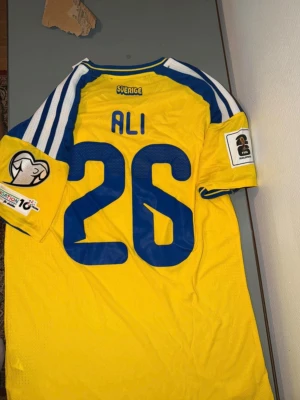 Sverige matchtröja gul/blå taha Ali - Säljer en officiell gul och blå matchtröja från Sveriges landslag med (Taha) Ali o 26 på ryggen.  Tröjan är helt ny och oanvänd.
