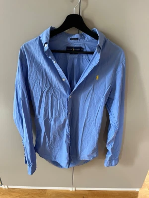 Blå skjorta från Ralph Lauren - Klassisk blå skjorta från Ralph Lauren i slim fit-modell. Skjortan är tillverkad i ett väldigt luftigt material. Skick 10/10 nypris 1899kr säljs 499kr pris kan diskuteras!
