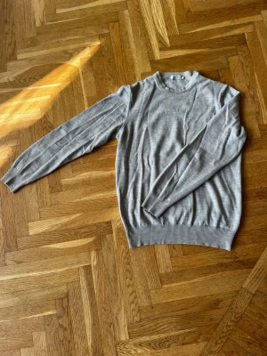 Grå stickad tröja från J.Lindeberg - Snygg grå stickad tröja från J.Lindeberg i storlek M. Tröjan har rund halsringning, långa ärmar och ribbade muddar vid ärmslut och nederkant. Storlek M men är liten passar perfekt på S