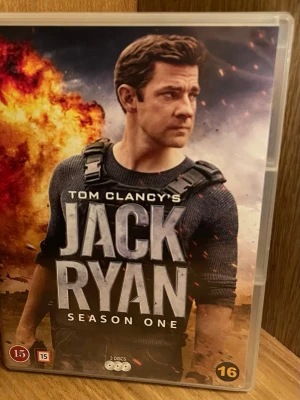 Tom Clancy's Jack Ryan Säsong 1 DVD - Jack Ryan Säsong 1 på DVD med tre skivor. Omslaget har en actionfylld design med explosion i bakgrunden och huvudkaraktären i fokus. Serien är en thriller med spännande special features och rekommenderas från 15 år. Perfekt Skick