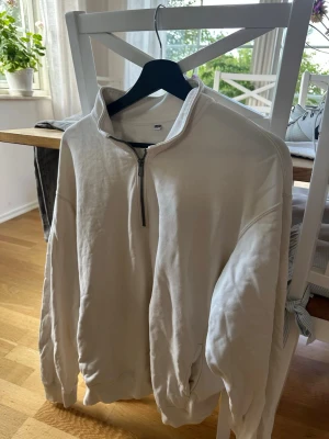 Vit halfzip hoodie - Säljer en stilren vit hoodie med halfzip och hög krage. Tröjan har långa ärmar, ribbade muddar och en avslappnad passform. Perfekt för dig som gillar en enkel men snygg look. Materialet känns mjukt och bekvämt. 