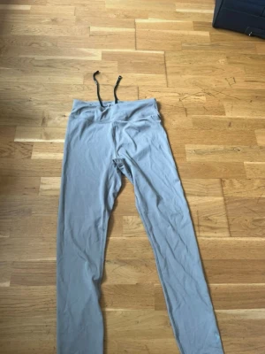 Grå leggings med dragsko - Snygga grå leggings med svart dragsko i midjan. Tillverkade i ett stretchigt och mjukt material som sitter skönt på kroppen. Perfekta för träning eller chill. Diskret logga på insidan av linningen.