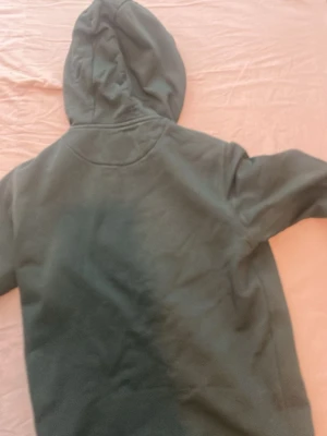 Mörkgrön hoodie med huva - En enkel och stilren mörkgrön hoodie med huva. Hoodien har långa ärmar och är gjord i ett mjukt material som känns skönt mot huden. Perfekt för dig som gillar en avslappnad och clean look.