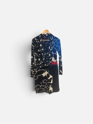 Mönstrad kortklänning med blommor - Unik kortklänning med svart och beige blommönster, inslag av rött och asymmetrisk design. Klänningen har lång ärm och omlott-look framtill. Perfekt för dig som gillar statement-plagg och coola detaljer. Size M