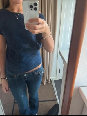 Mörkblå Nelly stickad topp med kort ärm - Mysig mörkblå stickad topp med korta ärmar och bred halsringning. Enkel och stilren design som passar perfekt till jeans eller kjol. Mjuk och skön kvalitet, troligtvis i ull- eller akrylblandning. Knappast använd 