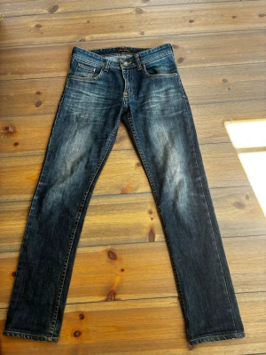 Mörkblå jeans från Nudie Jeans - Snygga mörkblå jeans från Nudie Jeans med slitningar och tvättade med raka ben 