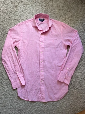 Rosa skjorta från Polo Ralph Lauren - Klassisk rosa skjorta från Polo Ralph Lauren med lång ärm och knappar framtill. Skjortan har en broderad logga på bröstet och är tillverkad i mjuk bomull. Perfekt till jeans eller chinos för en clean och stilren look. Kolla noga på alla bilder!❗️