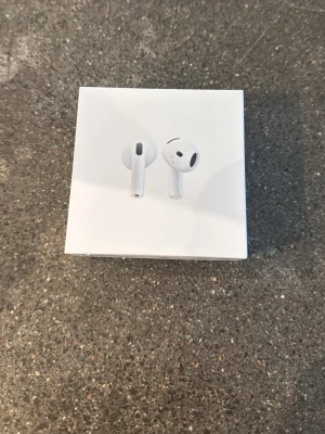  AirPods 4 Låda  - Säljer ett par stilrena vita trådlösa hörlurar från Apple. De har en smidig och kompakt design med rundade kanter och levereras i originalförpackning. Perfekta för musik, poddar och samtal på språng.