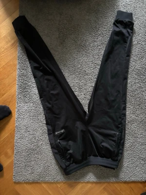 Svarta mjukisbyxor från Ellesse - Säljer ett par svarta mjukisbyxor från Ellesse med resår i midjan och muddar vid bensluten. Byxorna har fickor med dragkedja och en liten Ellesse-logga på ena benet. Perfekta för chill eller träning.