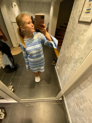 Blåvit randig stickad klänning - Mysig stickad klänning med blå och vita ränder. Modellen är kort med lång ärm och lätt utsvängda ärmslut. Klänningen har en öppen rygg och är perfekt för dig som gillar en avslappnad men ändå snygg stil.