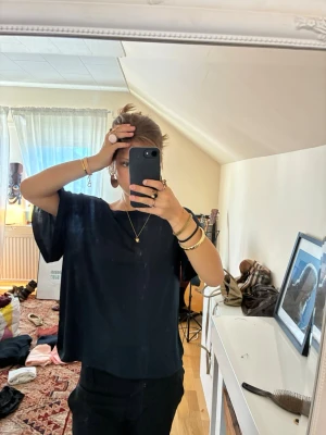 Mörkblå loose topp med kort ärm - En mörkblå, loose topp med korta ärmar och avslappnad passform. Toppen har en enkel, stilren design och är perfekt för dig som gillar en chill och bekväm look. Materialet känns mjukt och följsamt, troligen bomull eller polyester.