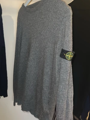 Stickad tröja från Stone Island i kashmir blend - Stickad grå tröja från Stone Island i en kashmir/ull mm blend. Köpte den på Kids Brand Store i NK för ett par år sedan. Storleken är junior 12, men jag skulle nog säga att den sitter mer som en vanlig XS eller kanske S. Måtten finns på de 2 sista bilderna. 