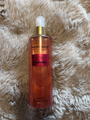 So Captivating Body Mist från Women’secret - Body mist från Women’secret i doften So Captivating. Flaskan är genomskinlig med skimrande orange glitter och har en guldig spraypump. Snygg rosa etikett framtill. Perfekt för dig som vill ha en fräsch och glittrig touch till din doftsamling.