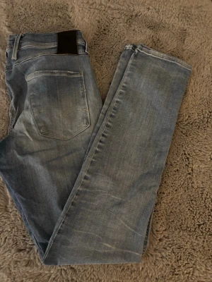 Ljusblå raka jeans - Säljer ett par ljusblå jeans med raka ben och klassisk femficksdesign. Jeansen har en snygg tvättad look och är tillverkade i denim. Passar perfekt till en avslappnad stil och har bälteshällor i midjan.