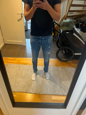 Replay anbass Slim fit ljusblå slitna jeans - Säljer ett par slim fit ljusblå jeans med slitningar och detaljerade sömmar. Jeansen har fem fickor och normal midja. Perfekta för dig som gillar en avslappnad men trendig stil. Materialet är klassisk denim i bomull.  Replay anbass används 1 gång 