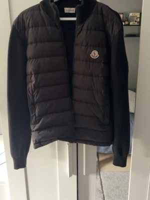 Moncler cardigan  - Svart pufferjacka från Moncler med quiltad front och ärmar i mjukare material. Jackan har dragkedja framtill och Moncler-logga på bröstet. Snygg, stilren och perfekt för kyligare dagar. Skriv om du vill ha mer bilder. 