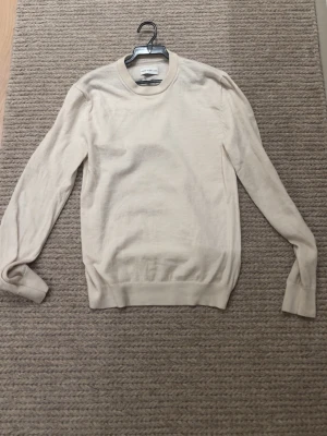 These glory days merinoull - Klassisk beige stickad tröja med rund halsringning och långa ärmar. Tröjan har ribbade muddar vid ärmslut och nederkant. Perfekt basplagg i mjuk ullmix som passar till det mesta. Tröjan är i bra skick, säljer då den är för liten. Hör av er vid frågor