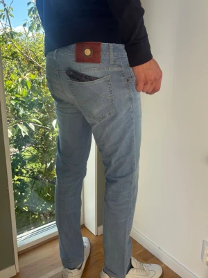Jacob Cohën 688 - Exklusiva Jacob Cohën 688 i premiumdenim med snygg tvätt och unika signaturdetaljer. Italienskt hantverk i mycket fint skick. Storlek 35 mer som en 32.  Skick: B Grade  Duk medföljer.  Är för liten i längden för mig i bilden som är 189 cm lång. Kolla mått nedan.  Mått:  Midja 44cm  Längd 99cm  Lår 30cm Benslut 18cm Tveka inte att höra av dig vid frågor eller funderingar.  Skickas snabbt!