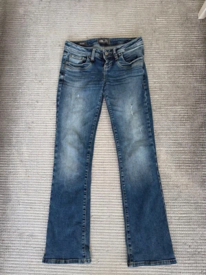 Blå bootcut jeans med slitningar - Blå LTB Low Rise Bootcut jeans i storlek 26/30. Väldigt fina och i bra skick. Innerbenslängd cirka 73,5 cm och midjemått cirka 37 cm mätt rakt över.