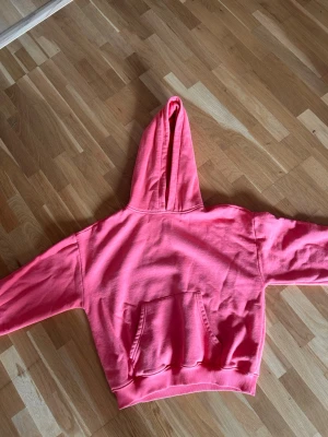 Mörk aprikos hoodie med magficka och huva - En snygg aprikos hoodie med klassisk huva och stor magficka framtill. Tröjan har ribbade muddar vid ärmslut och nederkant. Perfekt för dig som gillar en enkel men färgstark stil. Materialet ser ut att vara mjukt och bekvämt, troligen bomullsblandning.
