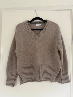 Beige stickad tröja från Wera - Mysig beige stickad tröja från Wera med v-ringning och bred ribbstickad kant nedtill och vid ärmsluten. Slitsar på sidorna. Perfekt till hösten😊
