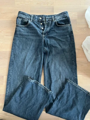 Jeans från Massimo Dutti - Säljer ett par mörkblå jeans med raka ben och mellanhög midja (midwaist). Jeansen har klassisk femficksdesign och stängs med knappar framtill. Materialet är i bomull och passformen är avslappnad. Helt oanvända! Nypris: 900kr