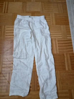 Vita linnebyxor från H&M - Säljer ett par vita linnebyxor från H&M i storlek 34. Byxorna har regular fit, resår i midjan och är gjorda i tunt, luftigt linne. Perfekta för en avslappnad och stilren look under varma dagar.