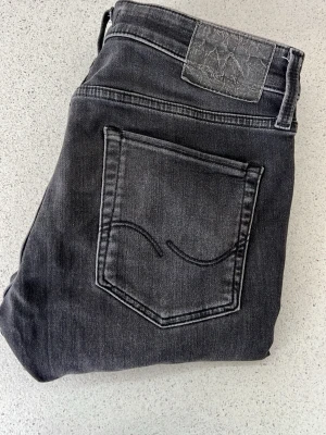 Slim Glen jeans  - Snygga grå slim fit jeans i modellen Slim/Glenn. Jeansen har klassisk femficksdesign, svarta sömmar och en diskret tvättad look. Perfekta för dig som gillar en smalare passform och vill ha ett par stilrena jeans till vardags. W29 L32