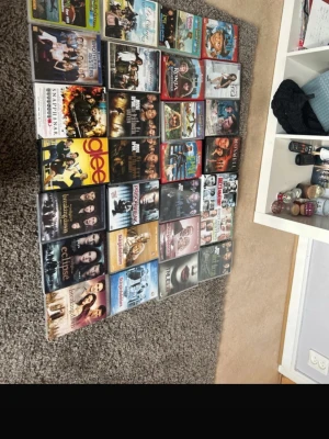 Samling med 28 DVD-filmer och serier - Stor samling med 28 olika DVD-filmer och TV-serier i färgglada plastfodral. Bland titlarna finns Glee, Twilight, The Hangover, och flera komedier, drama och action. Perfekt för dig som gillar filmkvällar och vill ha ett varierat utbud hemma.