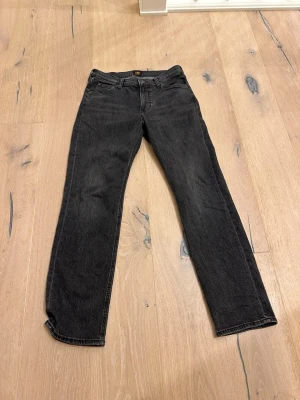 Svarta raka jeans från Lee - Snygga svarta jeans med rak passform och klassisk femficksdesign. Jeansen har normal midja och är tillverkade i ett mjukt denimtyg som ger en skön känsla. Perfekta för dig som gillar en stilren och enkel look.
