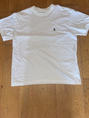 Vit slim fit t-shirt från Polo Ralph Lauren - Klassisk vit t-shirt från Polo Ralph Lauren i modellen Custom Slim Fit. Tillverkad i 100% bomull med rund halsringning och den ikoniska lilla broderade loggan på bröstet. Perfekt basplagg för en clean och stilren look.