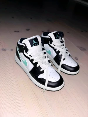 Nike Air Jordan 1 Mid White/Black/Green Glow - Säljer ett par Air Jordan 1s eftersom hann knappt använda de innan de blev för små, kan ha använts 3-5 gånger. På sista bilden ser ni nypris på skorna, de har även en liten fläck på bredsidan på en av skorna, som visas på bilder, kan dock tas bort i maskin eller liknande. #Jordan #Sneakers #Sale