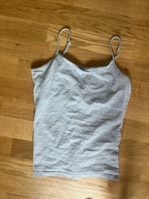 Ljusgrå linnetopp från Basic You - Säljer en enkel och stilren ljusgrå linnetopp från Basic You i ekologisk bomull. Toppen har smala axelband och ärmlös design, perfekt för varma dagar eller som lager under andra plagg.