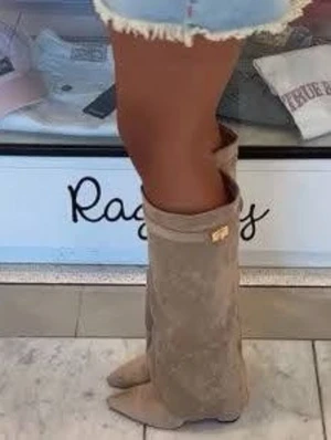 Beige höga mockastövlar - Snygga beige stövlar i mocka med slouchy passform och spetsig tå. Stövlarna har en dekorativ gulddetalj upptill och går upp till knäet. Perfekta för att lyfta din outfit till nästa nivå. Aldrig använd 