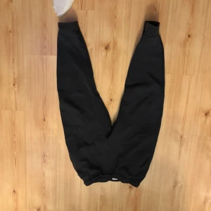 Svarta Nike mjukisbyxor med dragsko - Ett par svarta mjukisbyxor med resår i midjan och dragsko för justerbar passform. Byxorna har en avslappnad passform och är perfekta för chill dagar. Tillverkade i mjukt material som känns skönt mot huden.