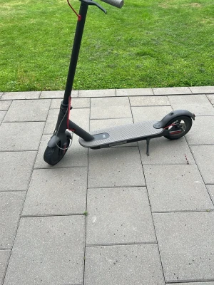 Svart elsparkcykel med röda detaljer - Säljer en svart elsparkcykel med röda detaljer och grått halkskydd på ståbrädan. Den har stora hjul, stöd och en minimalistisk design. Perfekt för att ta sig runt i stan på ett smidigt sätt. Har punka kommer med ett nytt däck. Kör i 27kmh med punktering.